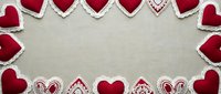 Red felt hearts and lace doilies arranged as decorative border frame on beige fabric background for Valentine's Day crafts, wedding invitations, romantic designs.