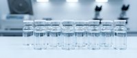 Empty glass vials arranged in rows on laboratory table in sterile medical research facility for pharmaceutical testing and drug development.