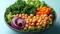 Fresh chickpea salad bowl with kale, red onion and cherry tomatoes on blue background. Healthy vegetarian meal prep concept for clean eating lifestyle.