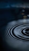 Abstract water ripples creating concentric circles on dark surface with bokeh lights in background for meditation and wellness concepts.