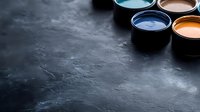 Colorful paint cans on dark textured background with dramatic lighting and copy space. Creative art supplies arranged in corner composition for design projects.