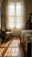 Cozy vintage bedroom with warm sunlight streaming through lace curtains onto wooden floors creating peaceful morning atmosphere for home decor inspiration.