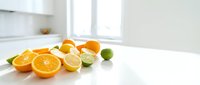 Fresh citrus fruits including oranges, lemons, and limes on a white kitchen counter, bright natural light, healthy eating concept.