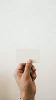 Caucasian male hand holding blank white card against neutral background, ready for custom text or branding design.