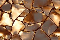 Shattered glass fragments in golden sunlight creating abstract pattern of broken pieces with sharp edges and warm reflective surfaces. Artistic macro photography.