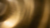 Smooth, blurred golden and bronze metallic surface with soft light reflections, suitable for backgrounds and design overlays.