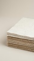 Stack of handmade recycled paper sheets with natural fibers and texture on neutral background for eco-friendly craft and stationery projects.