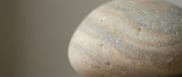 Smooth polished stone with natural striped patterns and speckled texture on neutral background for spa wellness meditation and zen decoration concepts.