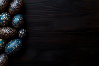 Decorated Easter eggs in blue and gold traditional patterns on dark wooden background with copy space for seasonal holiday designs.