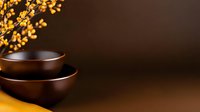 Minimalist brown ceramic bowls against dark background with glowing yellow autumn leaves, creating zen atmosphere for spa and wellness concepts.