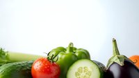 Fresh organic vegetables including tomato, cucumber, bell pepper and eggplant arranged on white background for healthy cooking and nutrition concepts.