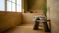 Zen spa bathroom interior with wooden stool, bamboo plant and natural stone textures creating peaceful meditation space for wellness and relaxation.