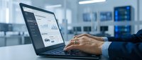 Professional businessman analyzing financial data and charts on laptop computer in modern office environment for business analytics and reporting.