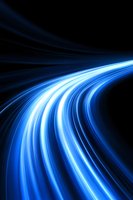 Dynamic blue light trails curve against dark background creating sense of speed, motion and energy flow. Abstract design for technology and innovation concepts.