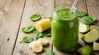 Fresh green smoothie with spinach, banana and apple in glass jar on rustic wooden table for healthy breakfast and detox nutrition lifestyle.
