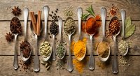 Aromatic spices and herbs collection in wooden spoons on rustic table. Culinary ingredients for cooking, seasoning and flavoring dishes in kitchen.