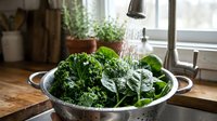 Fresh kale being rinsed in colander under running water in kitchen sink, preparing healthy vegetables for cooking or salad preparation.