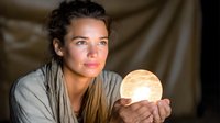Young woman holding glowing moon lamp in cozy bedroom setting. Spiritual wellness and mindfulness concept for relaxation and meditation practices.