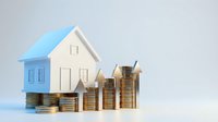 Small paper house model with stacked coins showing real estate investment growth and property value increase concept for financial planning.