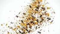 Mixed seeds and grains scattered on white background including sunflower seeds, sesame, quinoa and various cereals for healthy nutrition and cooking.