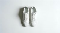 Pair of clean white leather sneakers shot from above on a light background, showcasing minimalist style and casual footwear design.