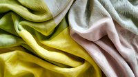 Soft flowing fabric in gentle pastel colors of pink, lime green and mint creates elegant waves and folds with delicate texture and natural light effects.