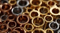 Assortment of metallic rings in gold, silver, and copper tones arranged closely together, creating a luxurious jewelry background.