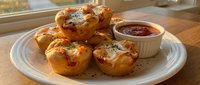 Golden baked egg muffins with cheese and herbs served on white plate with tomato sauce for breakfast or brunch meal preparation.