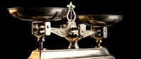 Vintage brass balance scale with two metal pans on dark background, antique weighing instrument for justice, law, pharmacy or kitchen measurement concepts.