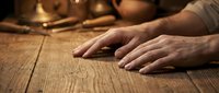 Skilled craftsman hands working on weathered wood surface in warm workshop lighting showcasing traditional woodworking artistry and craftsmanship techniques.