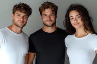 Three young diverse friends smiling together in casual t-shirts against neutral background for lifestyle and friendship concepts.