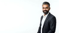 Middle-aged man with dark hair and full beard, South Asian ethnicity, wearing dark blazer over white shirt. Professional business portrait isolated on white background for corporate use.