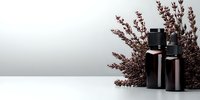 Dark glass essential oil bottles with dried burgundy flowers on white surface against light background, minimalist spa and wellness composition.