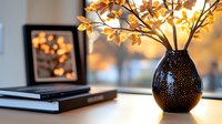 Autumn branches with golden leaves in decorative vase on table with books and warm lighting creating cozy seasonal home interior atmosphere.