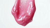 Glossy pink gel or liquid cosmetic product with smooth, flowing texture and reflective surface against white background for beauty and skincare marketing.