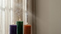 Three colorful pillar candles burning with gentle flames creating peaceful ambiance in soft natural light for relaxation and home decor.