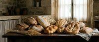 Assorted freshly baked artisan breads including whole grain, sourdough and crusty loaves arranged on wooden table in rustic bakery setting for food and culinary use.