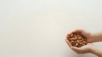 Handful of almonds held in open palms against neutral background, suitable for nutrition, health, wellness, and food packaging design projects.