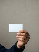 Close-up of mature man's hand holding blank white card against neutral gray background. Ideal for business, networking, and professional communication concepts.
