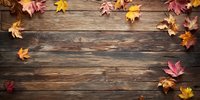 Autumn maple leaves scattered on rustic wooden planks, creating seasonal border frame on weathered barn wood background.