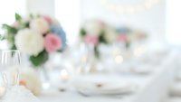 Elegant wedding table setting with champagne glasses and soft floral arrangements in pastel colors creating romantic atmosphere for celebration.