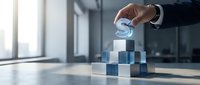 Businessman hand placing glowing dollar sign symbol on stacked blue and white blocks, representing financial growth, investment strategy, and business success in modern office setting.