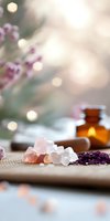 Pink himalayan salt crystals and dried lavender with amber essential oil bottle on bamboo mat, soft bokeh background creates serene spa atmosphere.