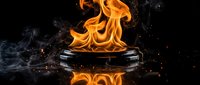 Dramatic orange flames erupting from black cauldron with smoke and sparks against dark background for cooking and fire concepts.