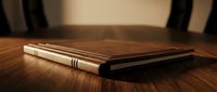 Elegant leather-bound journal with golden details resting on polished wooden surface in warm ambient lighting for writing and note-taking projects.