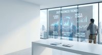 Modern office with businessman analyzing digital business trends dashboard on smart glass window displaying financial charts and data analytics.