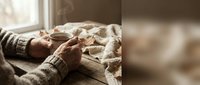 Elderly hands holding warm cup in cozy sweater by window with soft natural light creating peaceful morning atmosphere for relaxation and comfort.