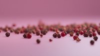 Fresh pink and red peppercorns scattered on pink surface with soft focus and shallow depth of field, creating minimalist food composition for culinary designs.