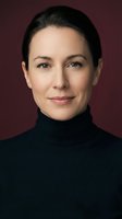 Professional middle-aged Caucasian woman in black turtleneck against burgundy background. Confident business executive portrait for corporate branding.