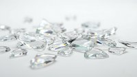 Scattered transparent glass shards and crystal fragments on white surface, suitable for luxury, jewelry, and design projects.
